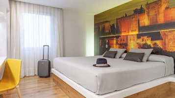 Ett hotellrum med en stor säng, en resväska, en gul stol och en väggmålning som föreställer ett slott.