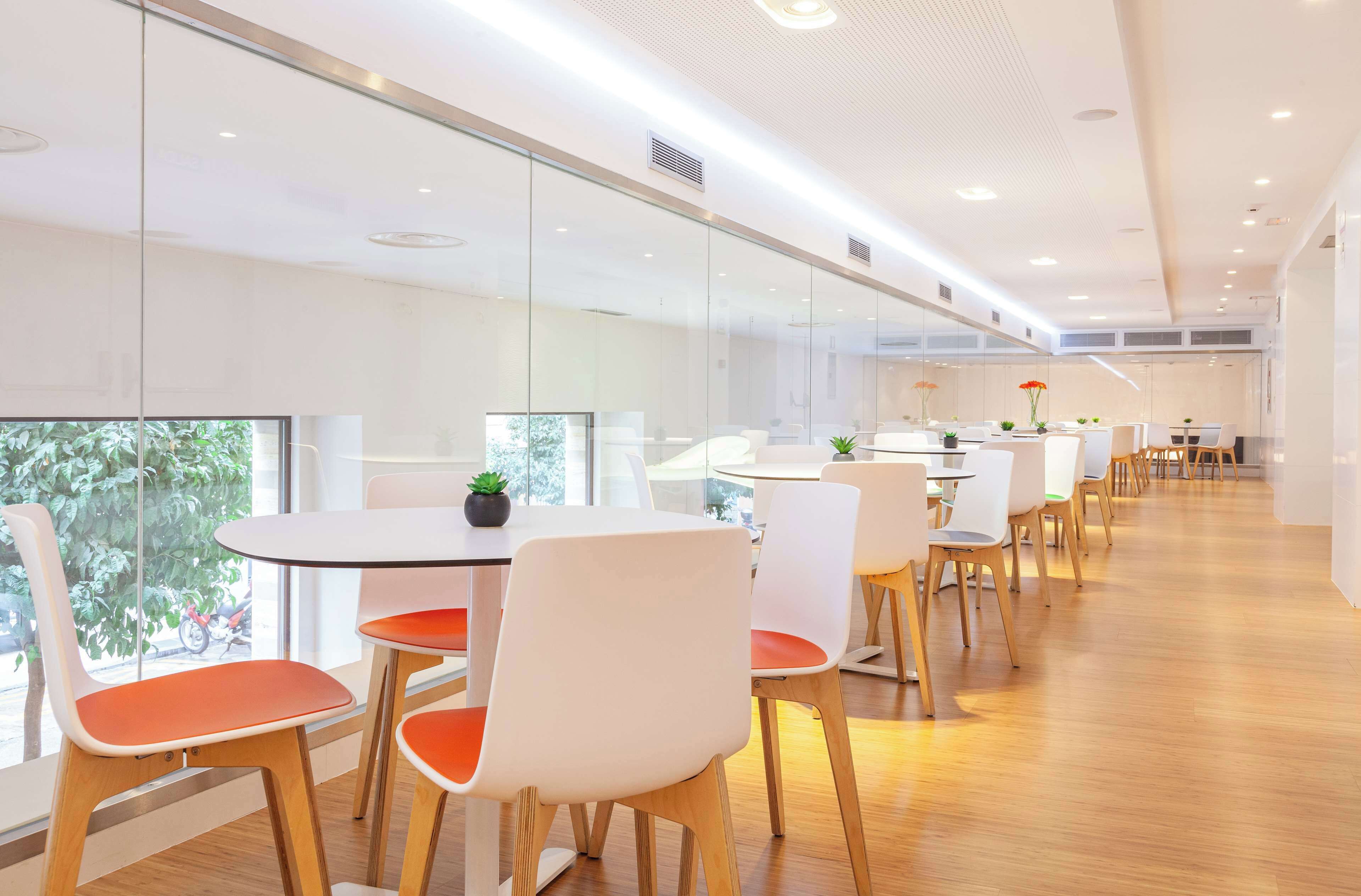 A modern conference room with glass walls, white chairs, and a wooden floor.