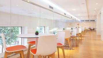 A modern conference room with glass walls, white chairs, and a wooden floor.