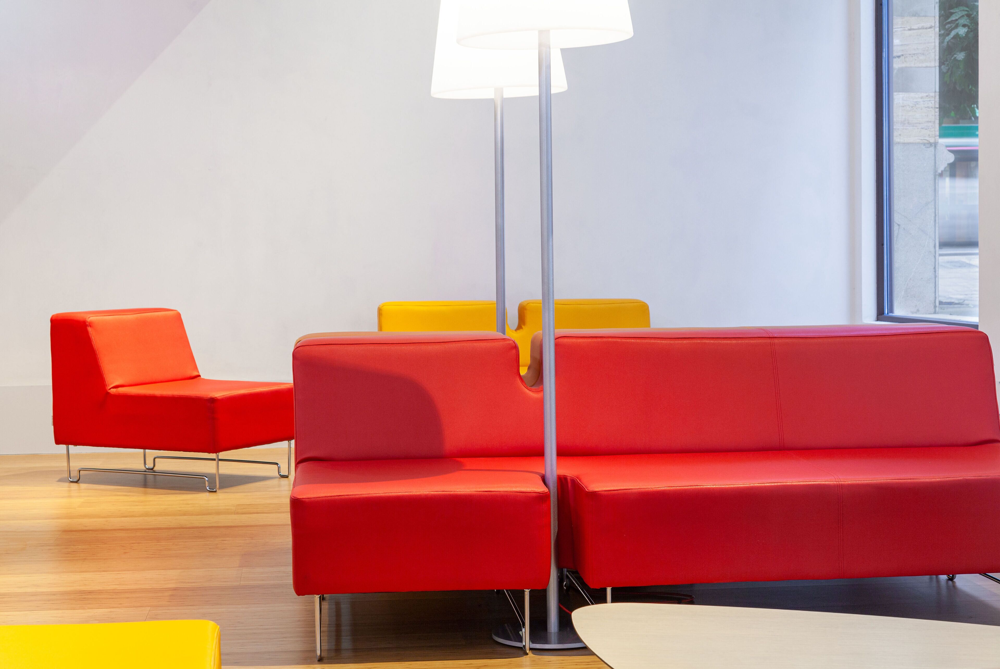Un interior moderno con un sofá rojo, sillas amarillas y una lámpara de pie.