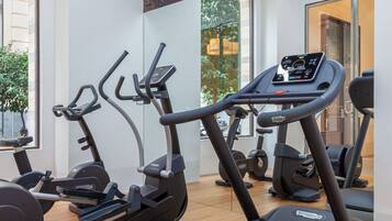 Un gimnasio con cintas de correr, elípticas y un espejo grande.