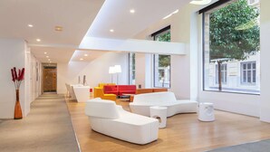A modern interior with white sofas, a red couch, and a white coffee table. - Hotel Macià Granada Five Senses Rooms & Suites (Granada)