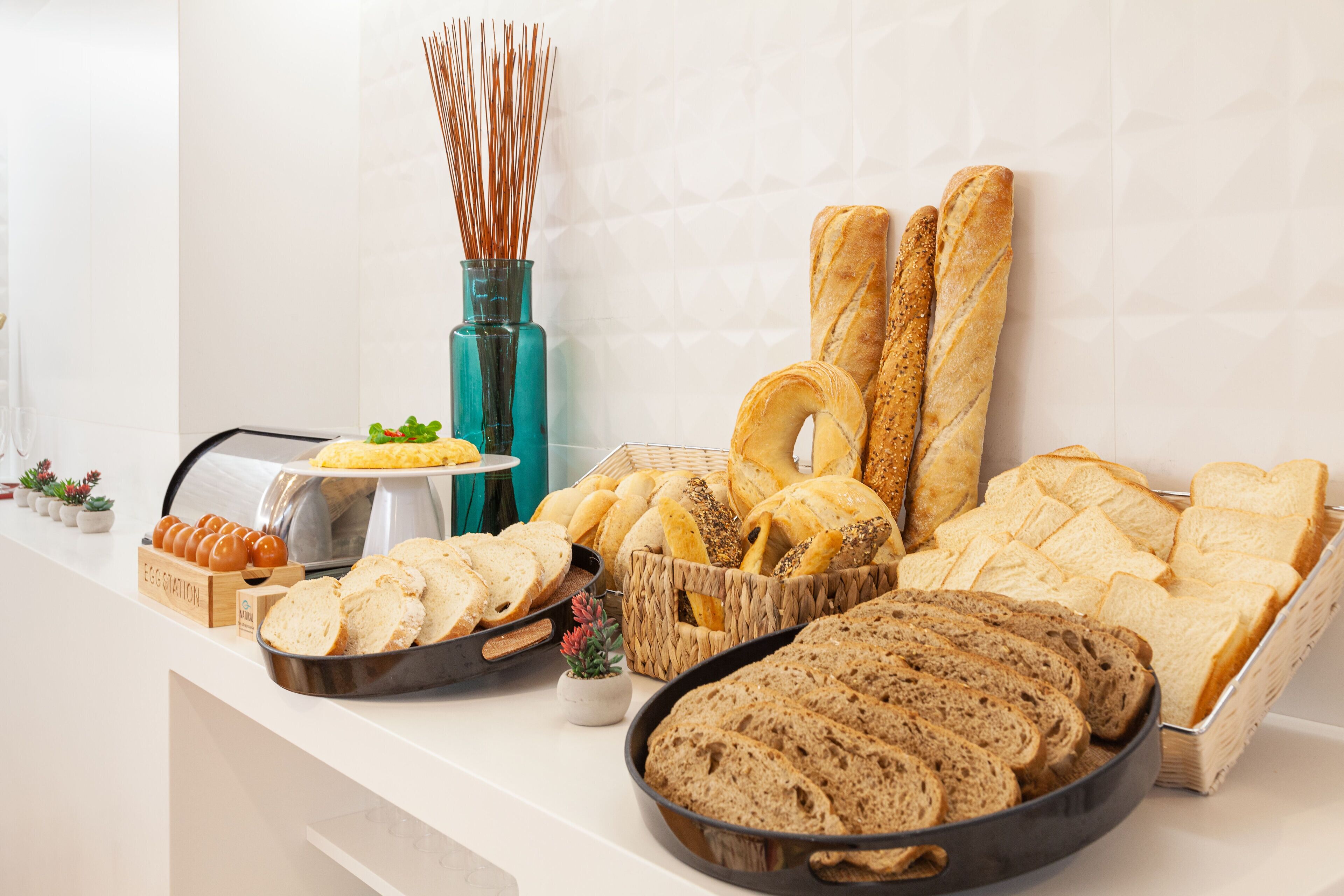 Een buffet met diverse broden, een schaal eieren en een decoratieve vaas.