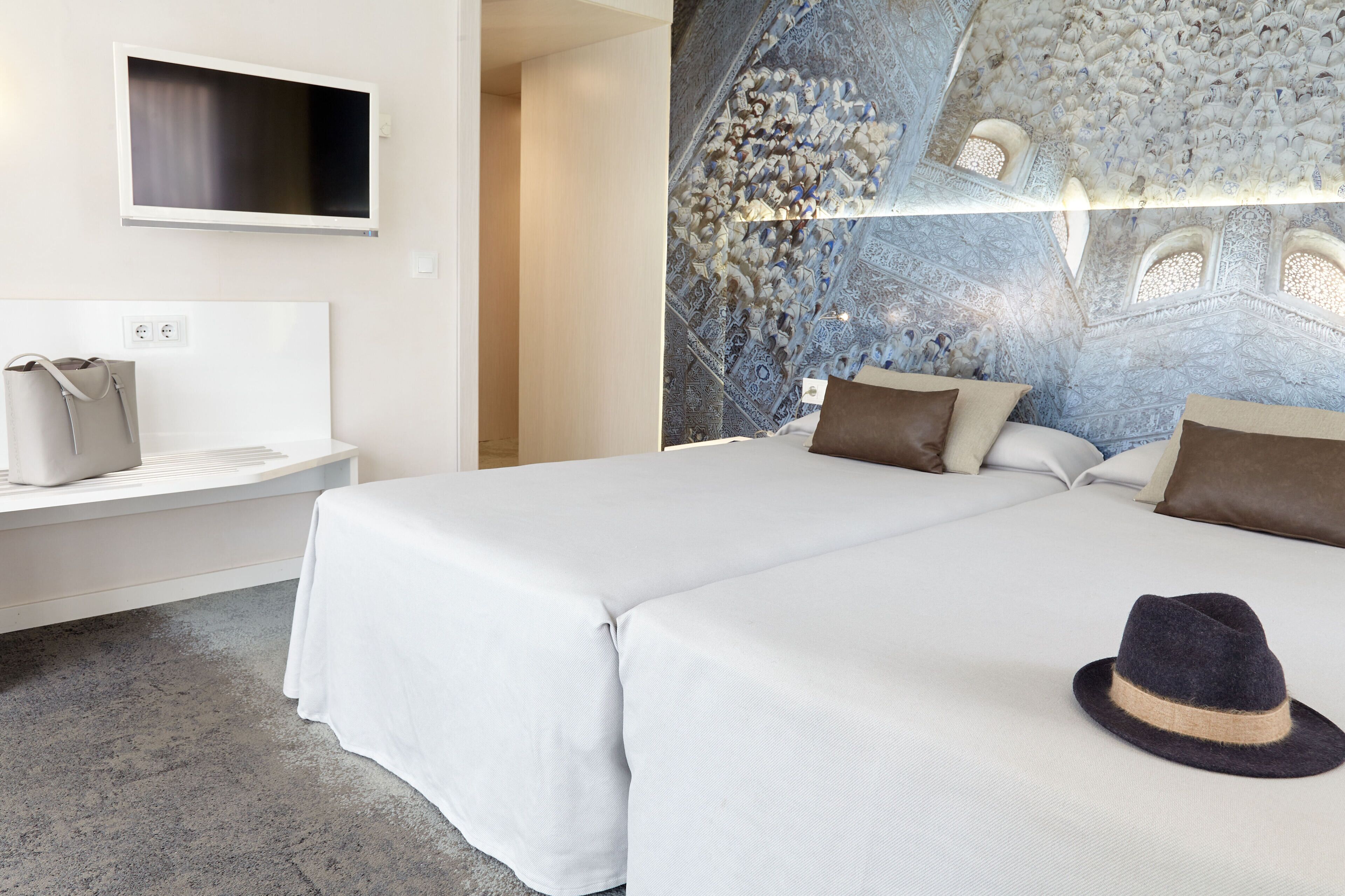 Una habitació d'hotel amb un llit gran, una televisió penjada a la paret i un sostre decoratiu.