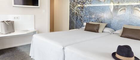 A hotel room with a large bed, a television mounted on the wall, and a decorative ceiling.