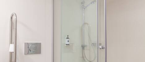 A modern bathroom with a glass-enclosed shower, a white toilet, and a blue-tiled floor.
