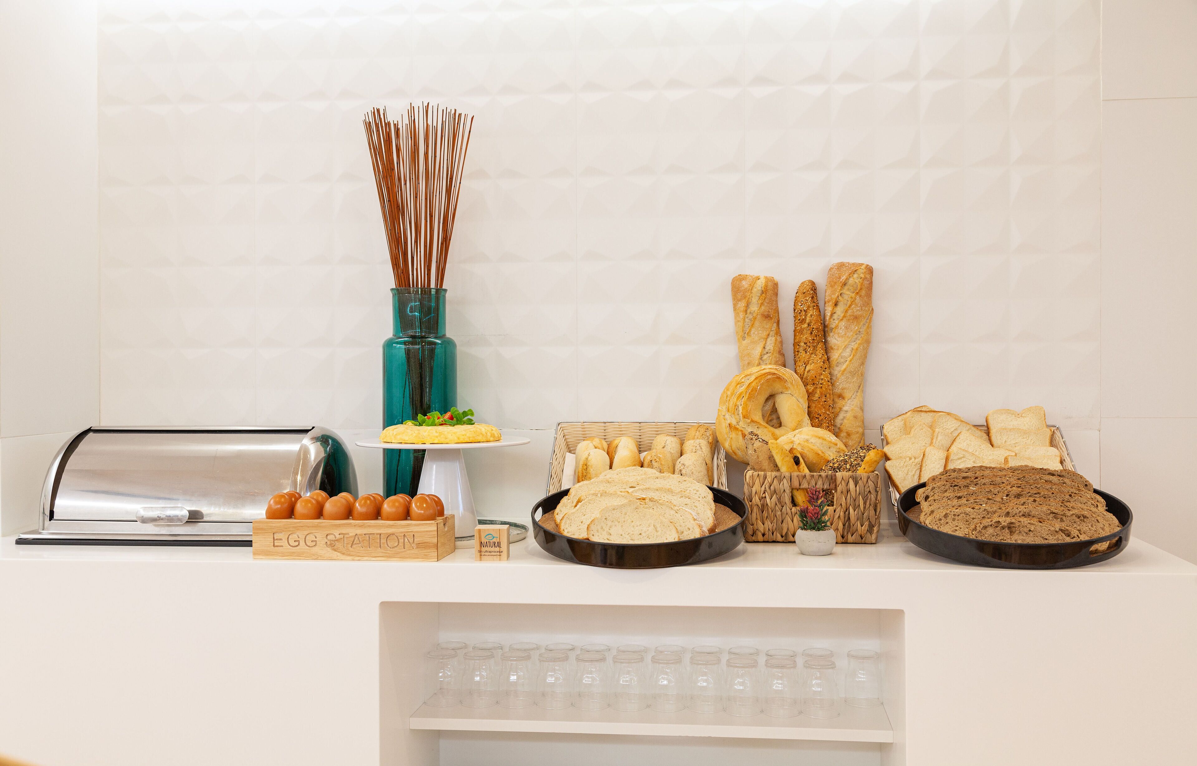 A breakfast buffet with various breads, pastries, and a toaster.