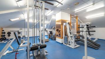 A gym with various exercise equipment, a blue floor, and a sloped ceiling.