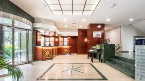 Rebedor d'hotel amb taulell de recepció, escala i un ampli disseny de sòl amb motius de les estrelles.