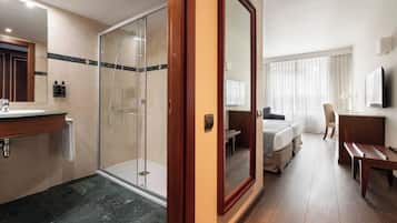 A hotel room with a shower, a bed, a desk, and a TV.