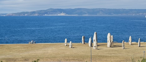 A coastal view with a grassy area, stone structures, and a body of water.