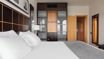 Una habitación de hotel con una cama grande, un armario con espejo y una puerta que da a otra habitación.
