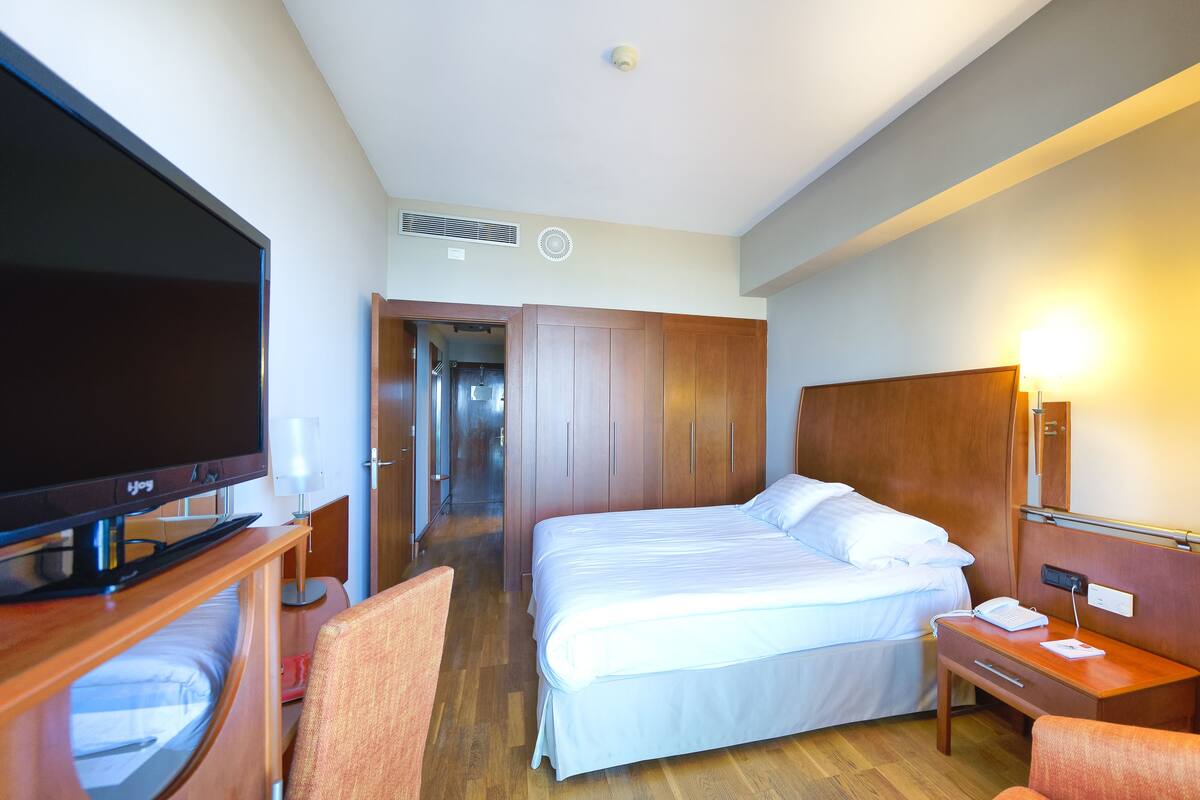 Une chambre d’hôtel équipée d’un lit, d’un bureau, d’une chaise, d’une télévision et d’une lampe.