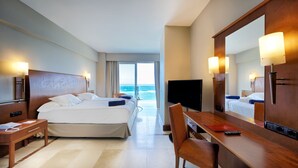 Habitación de hotel con una cama grande, un escritorio, una silla, un televisor y vista al océano.