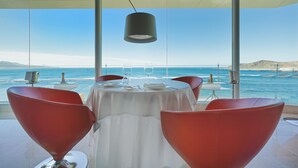 Mesa de comedor preparada para dos personas, con vista al océano.