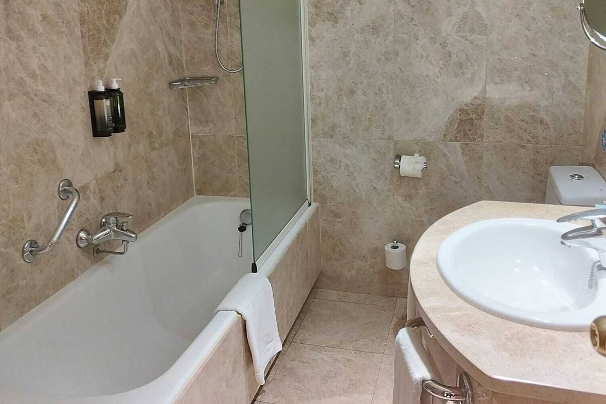 A bathroom with a bathtub, a shower, a sink, and a toilet.