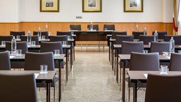 Un salón de conferencias con mesas y sillas, cuadros en la pared y un diseño de paneles de madera.