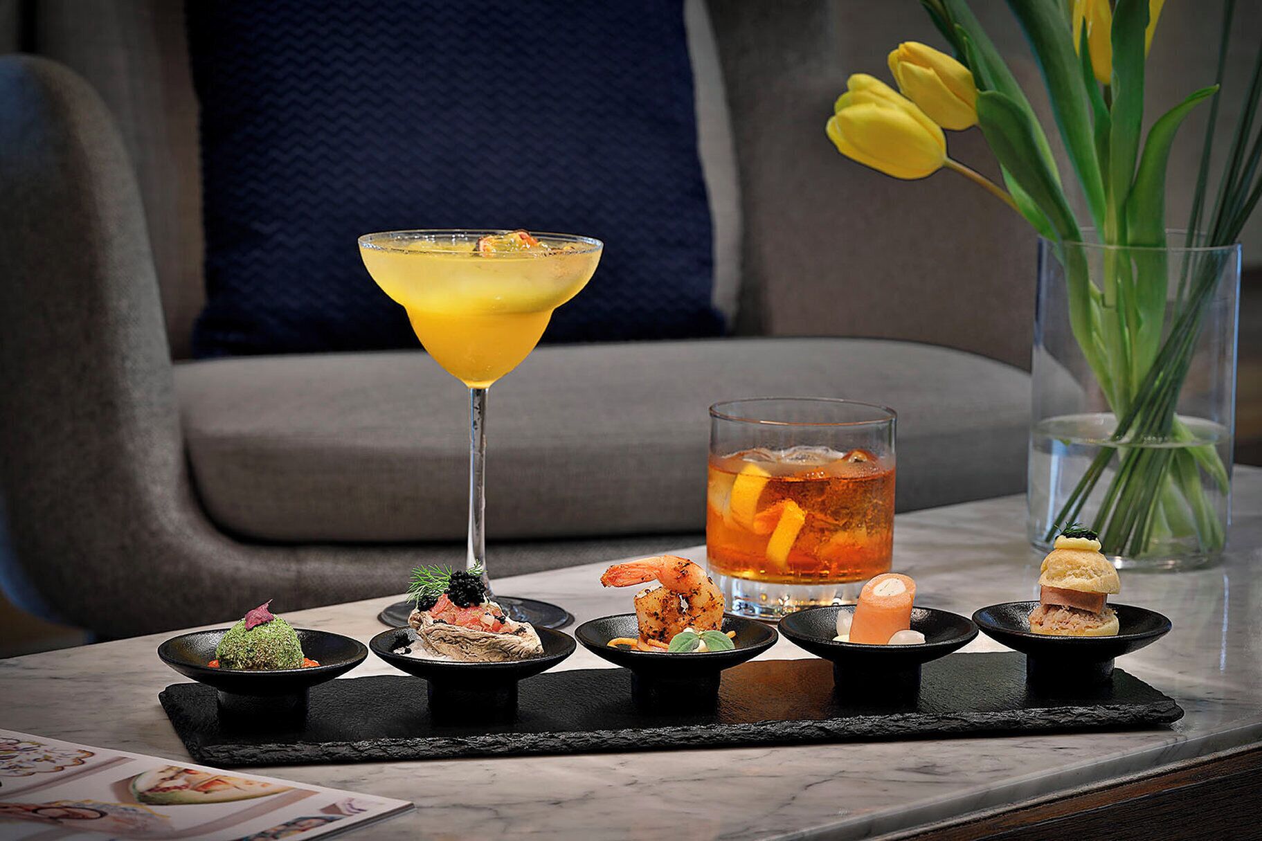 A table with a martini glass, a glass of iced tea, and various appetizers.