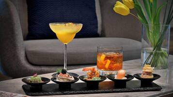 A table with a martini glass, a glass of iced tea, and various appetizers.