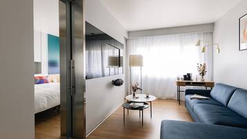 Una habitación de hotel moderna con una cama, un sofá, una mesita y un escritorio con una lámpara.