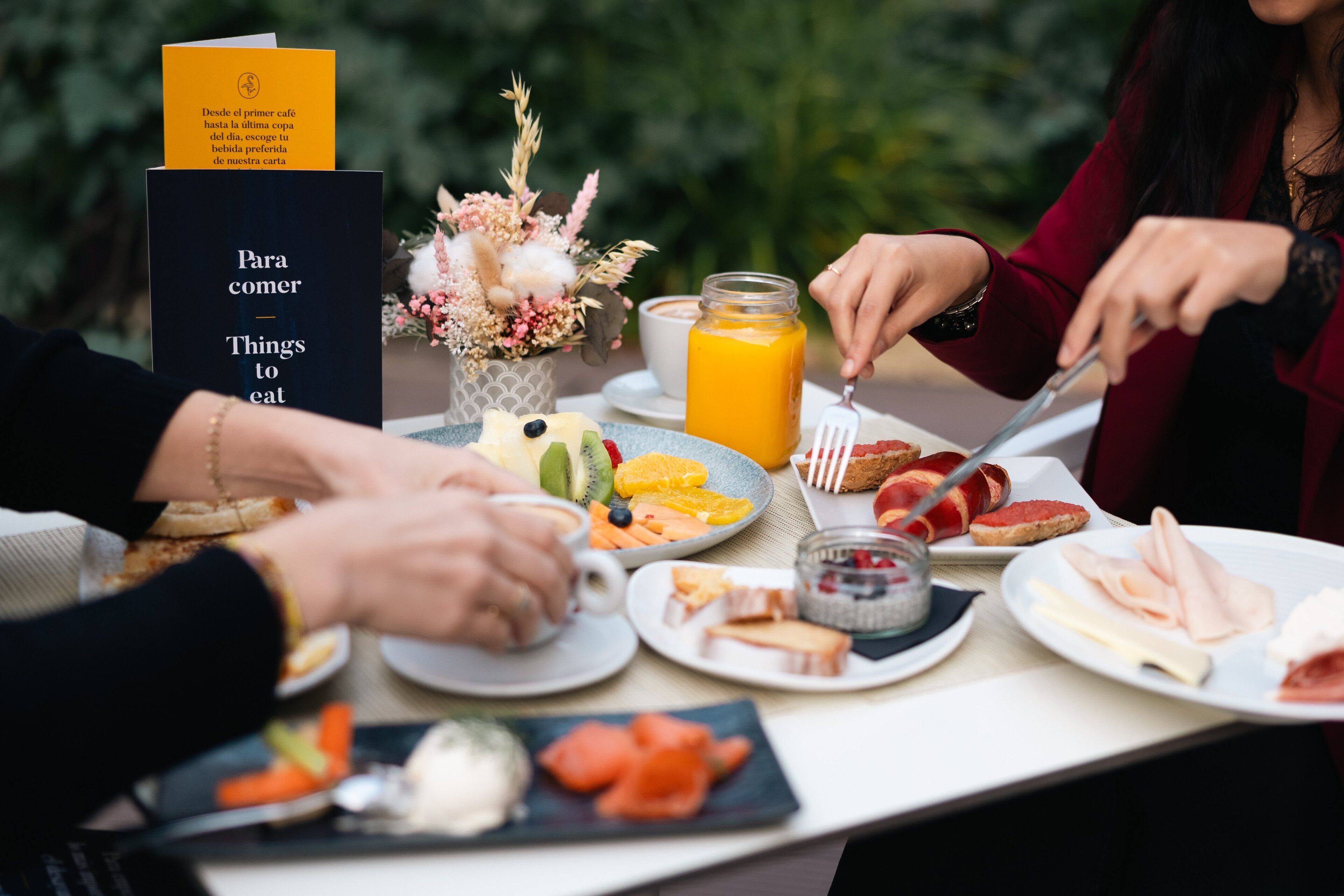 A table with various breakfast items, including fruits, bread, and a glass of orange juice.