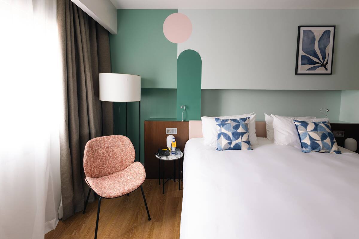 Ein Hotelzimmer mit Bett, Stuhl, Schreibtisch und Lampe.