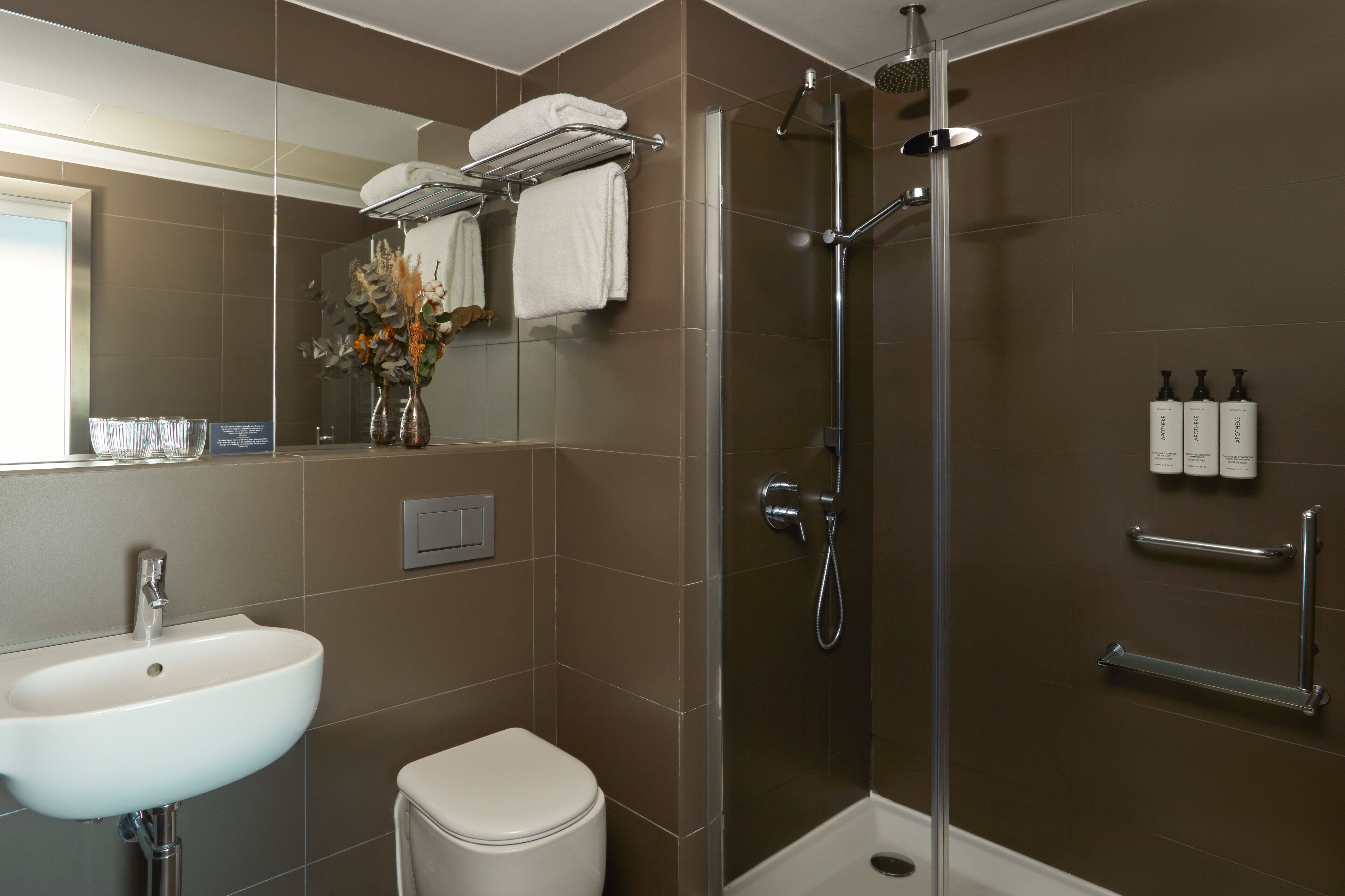 Un baño moderno con lavamanos, inodoro y ducha.