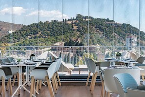 A restaurant with a terrace overlooking a hillside.