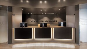 Ein moderner Hotelrezeptionstresen mit gebogenem Design, inklusive digitalem Display und Wartebereich.