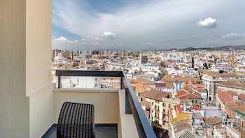 A balcony with a view of a densely packed cityscape, featuring a variety of building styles and a clear sky.