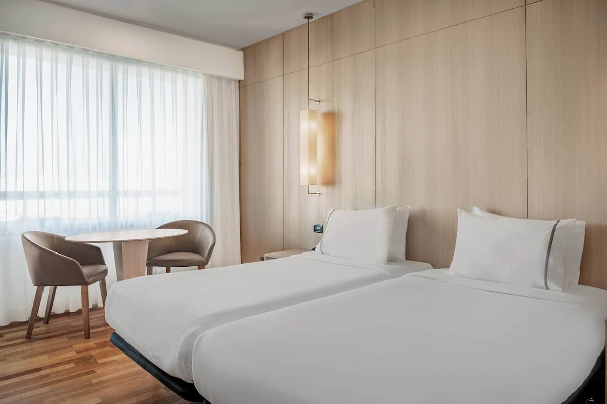 Een hotelkamer met twee bedden, een ronde tafel en een stoel.