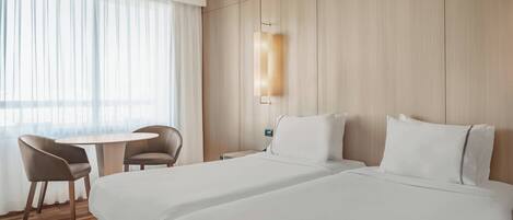 Une chambre d’hôtel avec deux lits, une table ronde et une chaise.