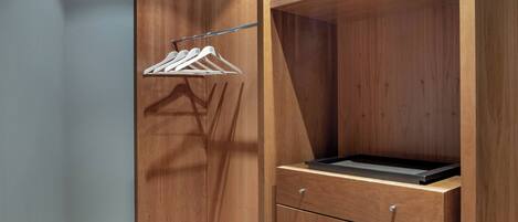 A wooden closet with a hanging rack and a drawer unit.
