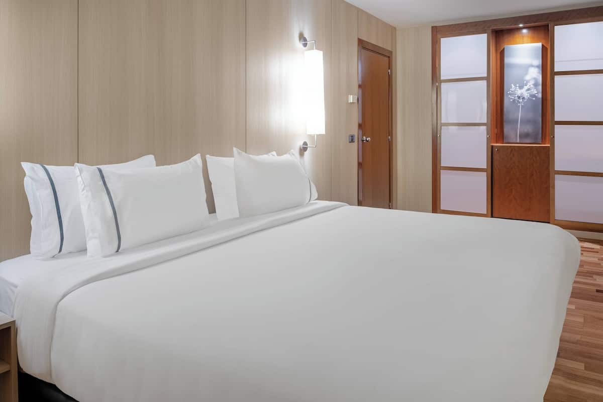 Een net opgemaakt bed met witte lakens en een houten hoofdbord.