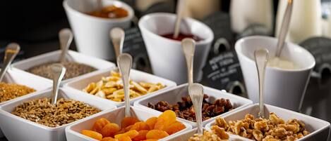 A variety of food items in white bowls with spoons, arranged on a table.