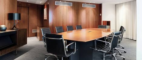 A conference room with a large wooden table, black chairs, and a modern design.