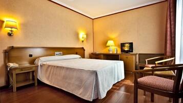 Minibar, escritorio, cortinas blackout y tabla de planchar con plancha