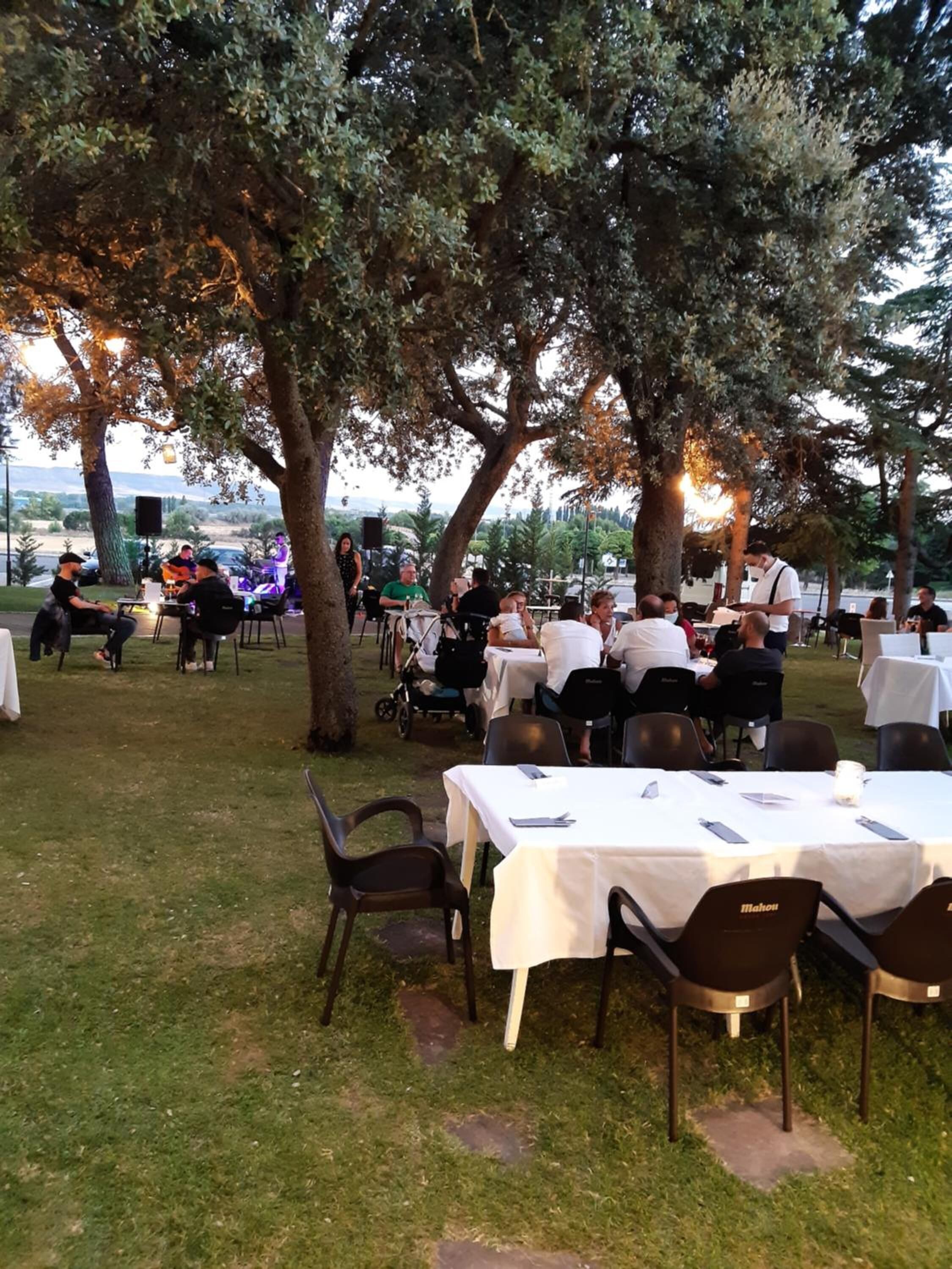 Un área de comedor al aire libre con mesas y sillas, rodeada de árboles y vistas al paisaje.