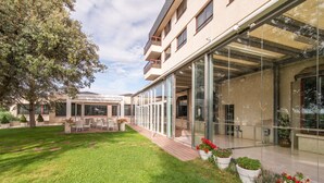Un edificio moderno con un área de estar al aire libre techada, un césped cuidado y plantas en macetas.
