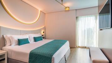 Una habitación de hotel moderna con una cama bien hecha, un banco y un ventanal con cortinas.