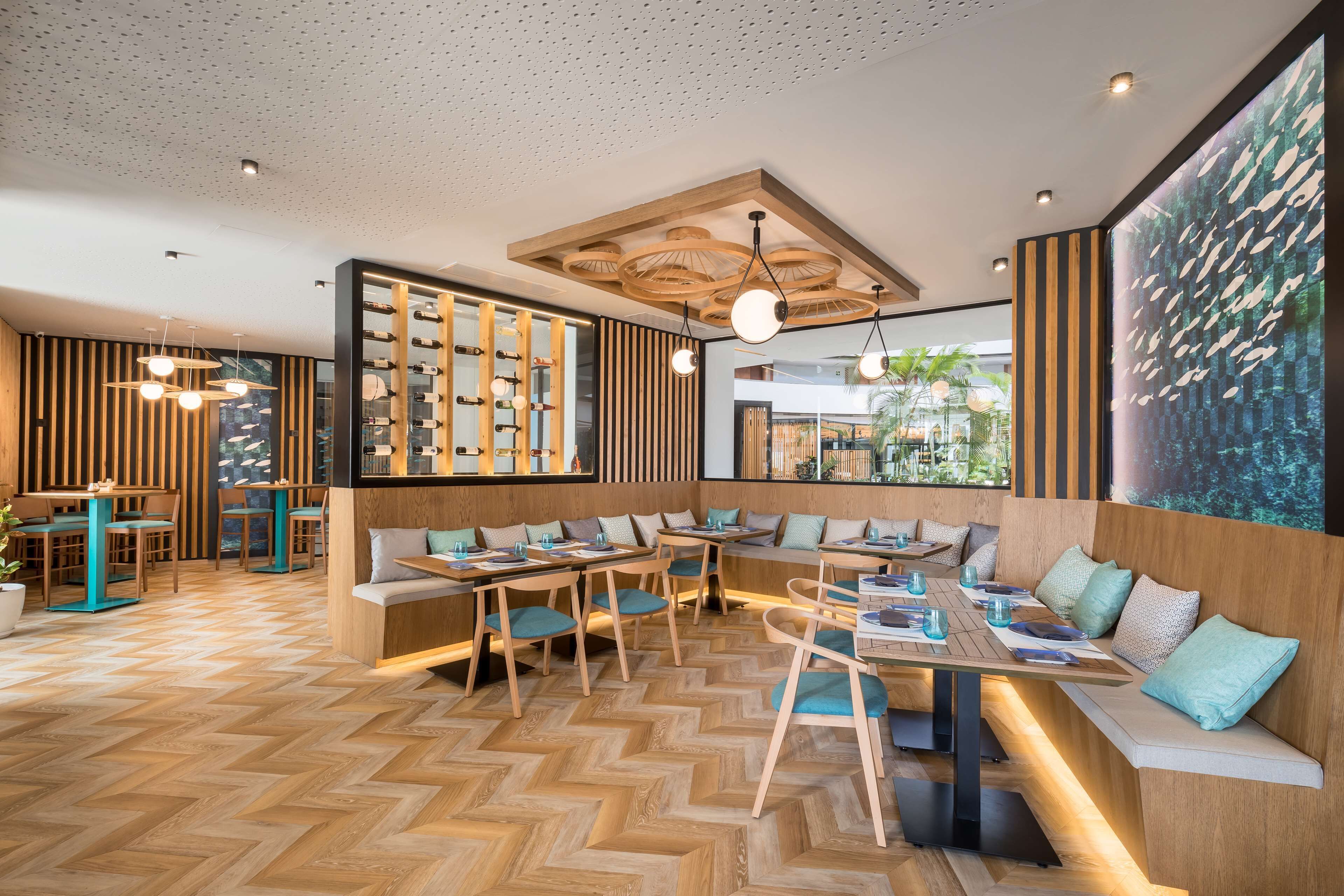 Un restaurante moderno con suelo de madera, asientos escalonados e iluminación colgante.