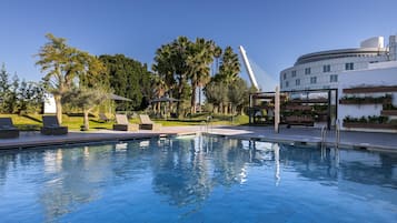 Relax by the pool surrounded by lush greenery and lounge chairs.