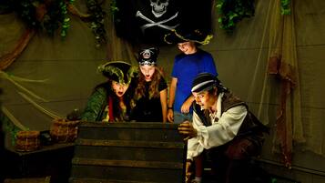 Un grupo de personas vestidas con trajes de pirata alrededor de un cofre de madera.