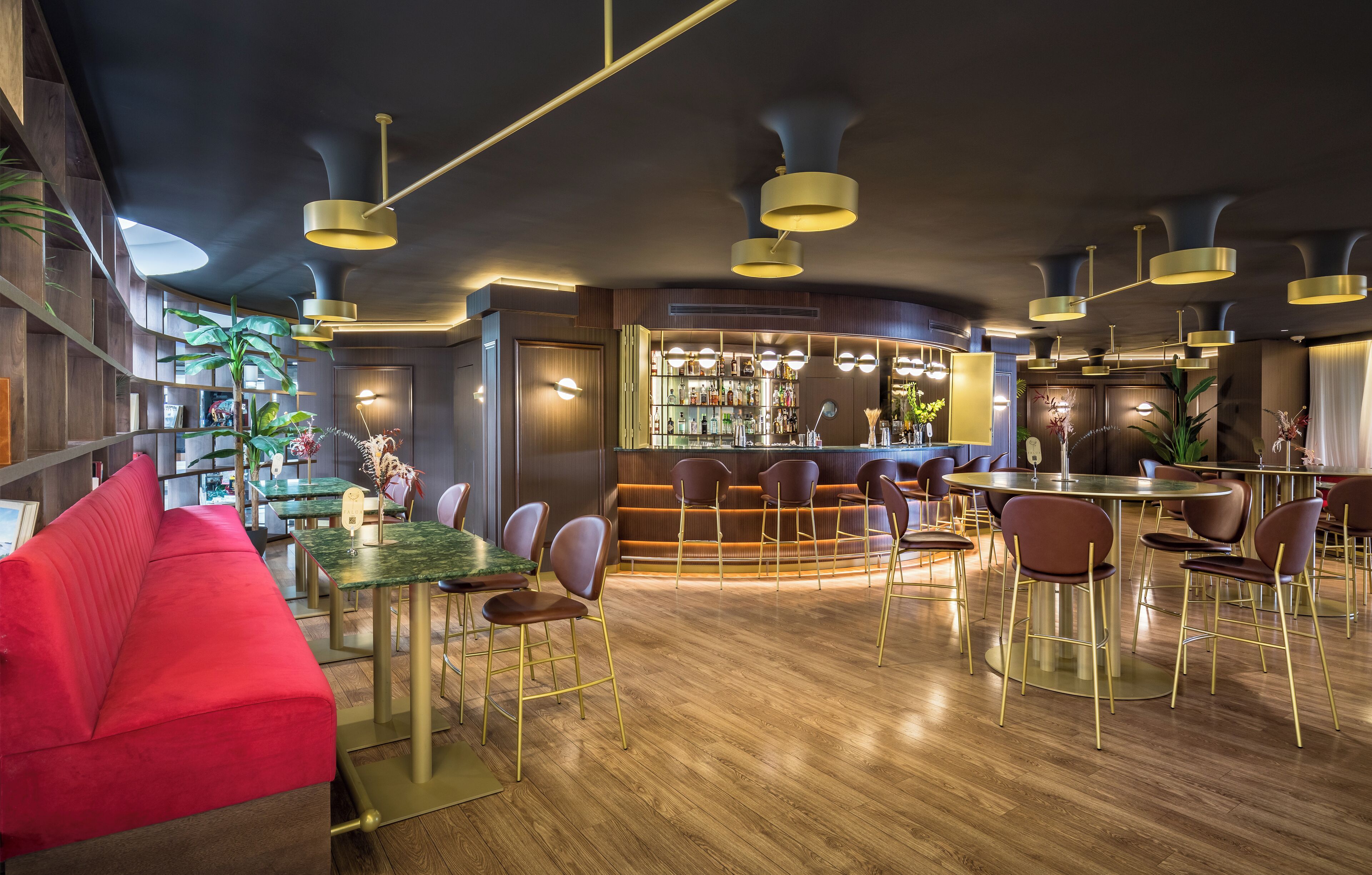Zona de bar moderna con suelos de madera, asientos rojos y una barra con una amplia selección de licores.