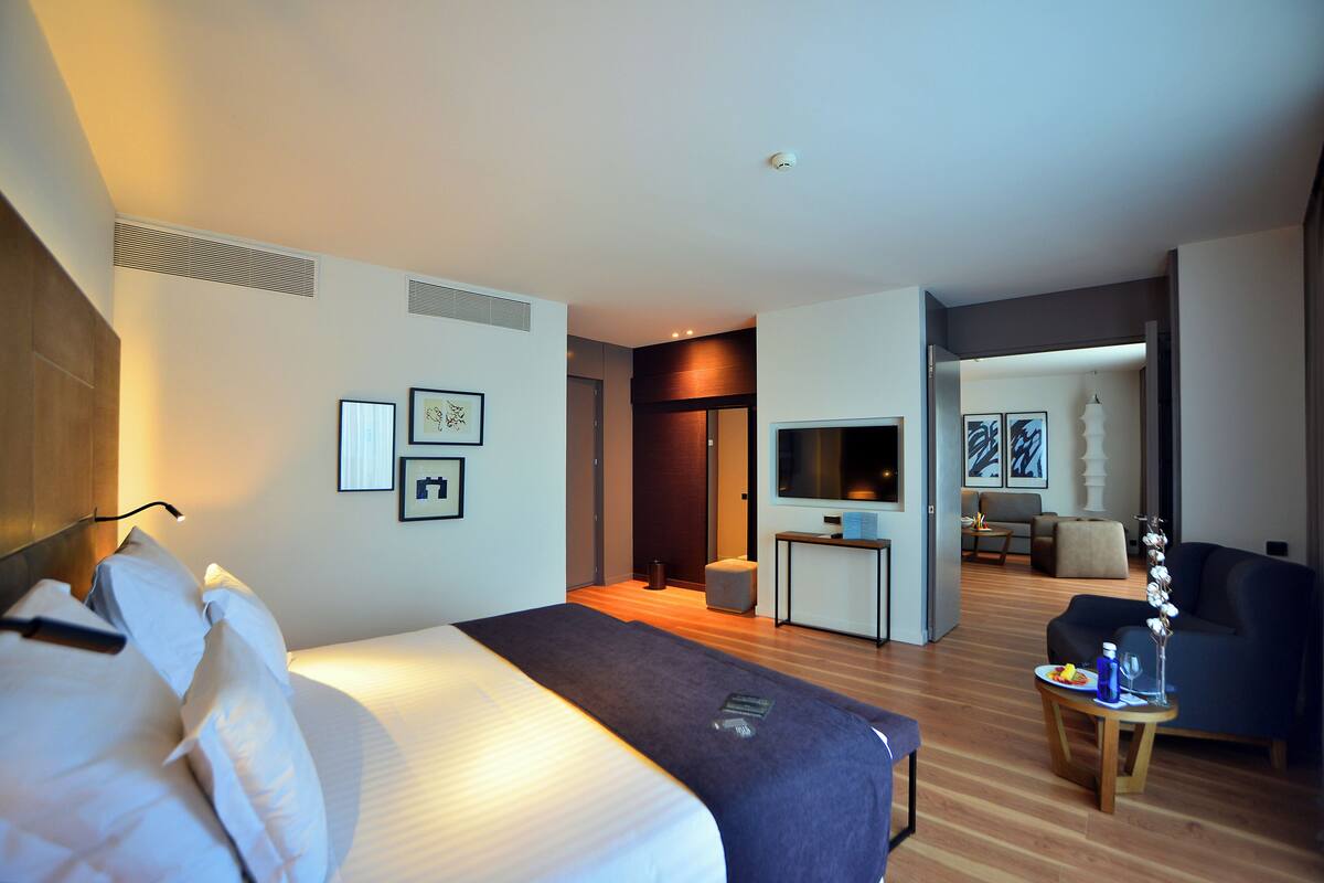 A hotel room with a bed, a desk, a chair, and a TV.