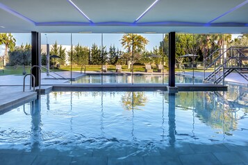 Una piscina cubierta, una piscina al aire libre de temporada, sombrillas