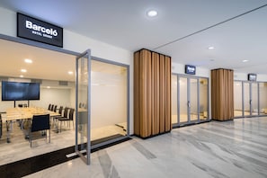 A modern hotel lobby with a conference room, glass doors, and wooden partitions.