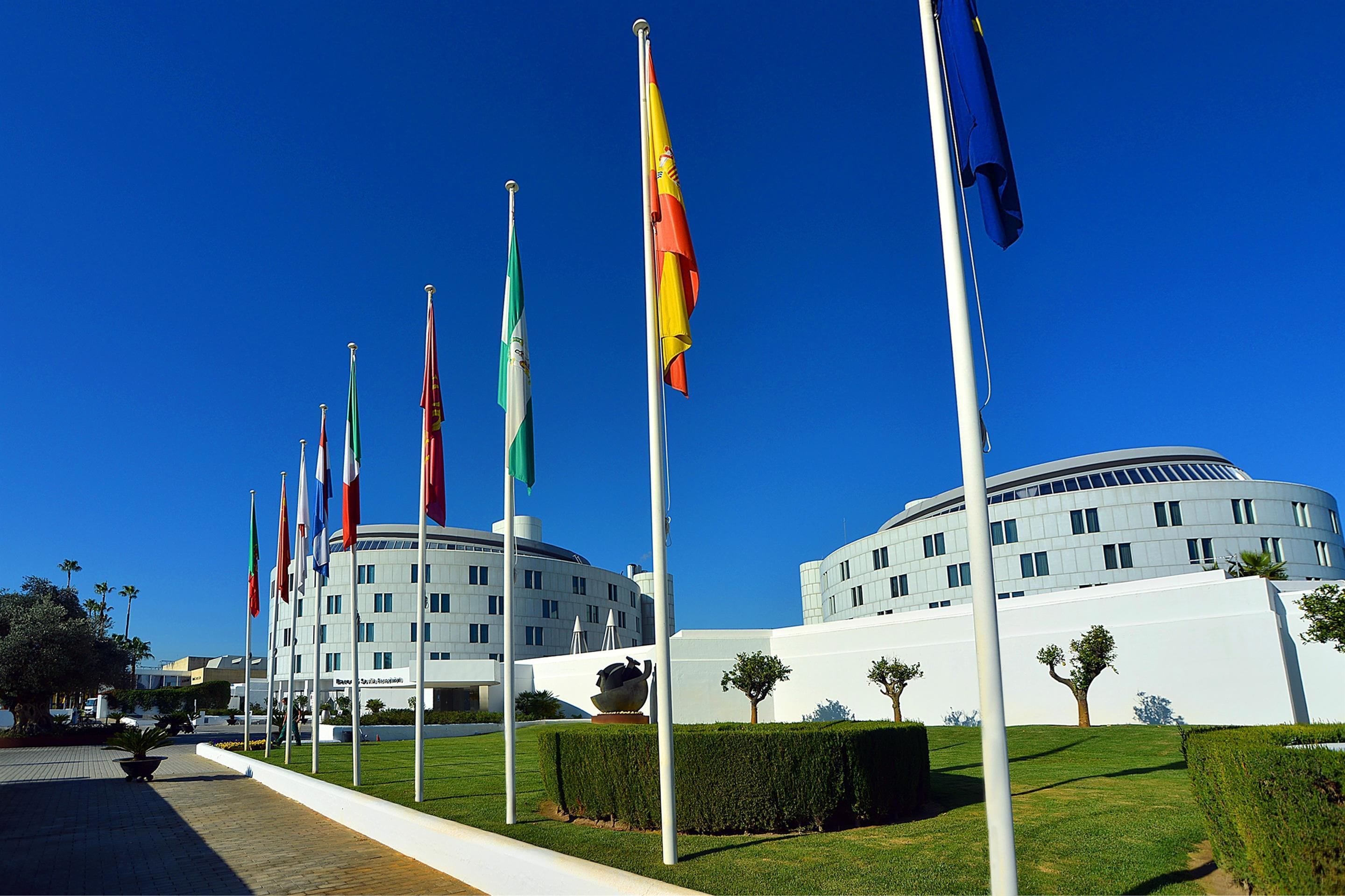 Un bâtiment orné de plusieurs drapeaux, doté d’une pelouse bien entretenue et présentant un design architectural moderne.