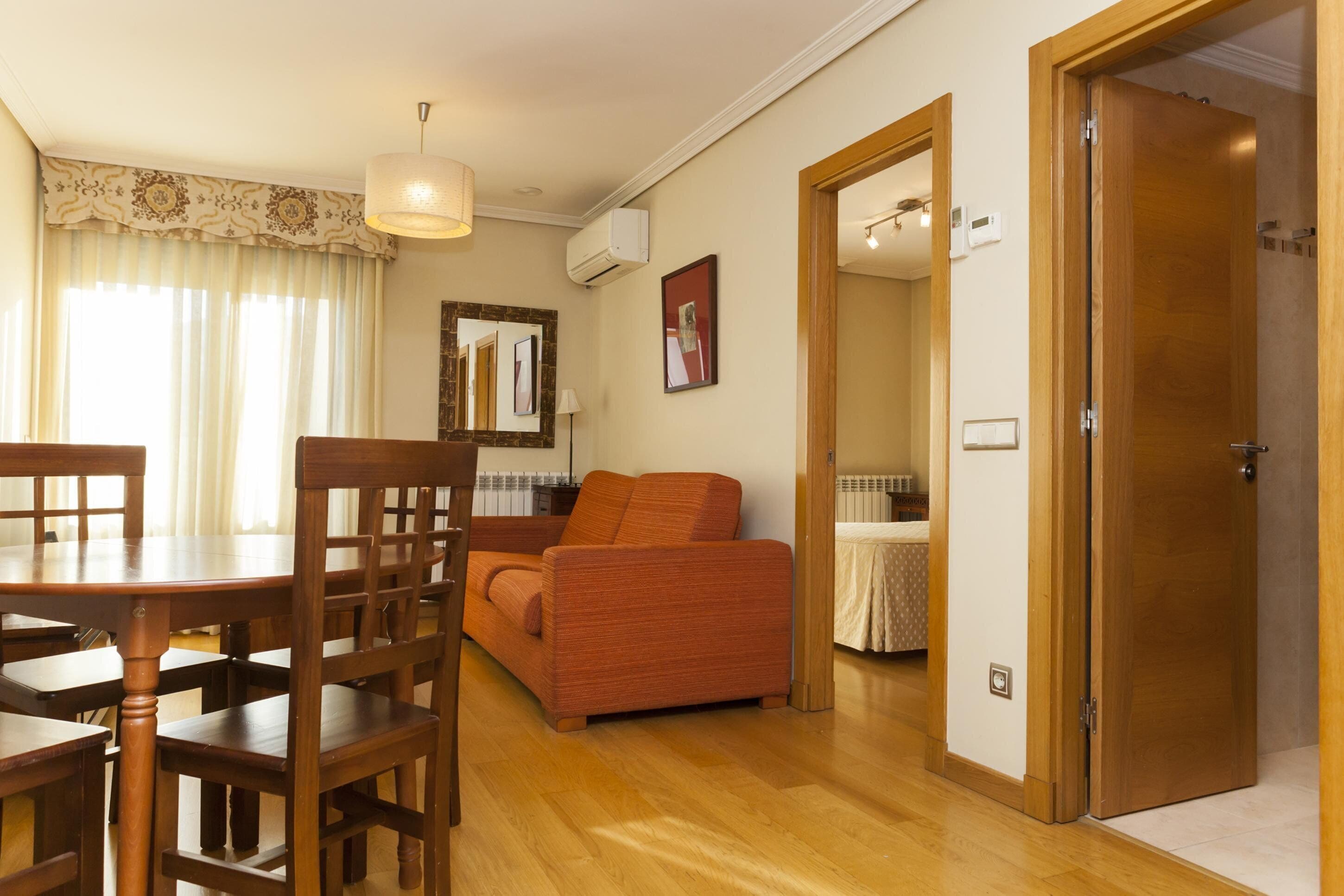Una habitación con una mesa de comedor, sillas, un sofá, un espejo y una puerta.