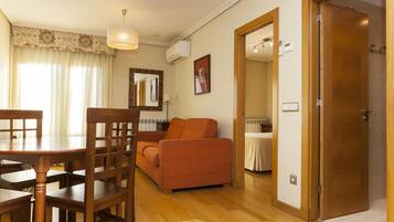 Una habitación con una mesa de comedor, sillas, un sofá, un espejo y una puerta.